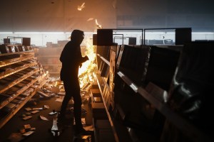 Protester feeds a fire with copy paper inside a Office Depot store in St. Paul, Minn.