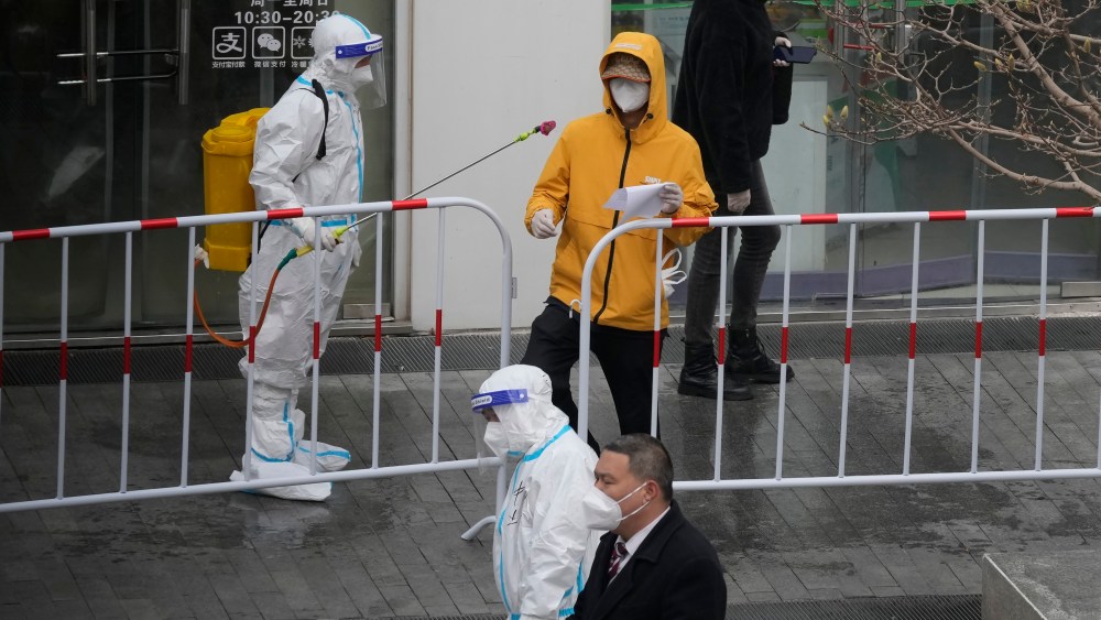 A worker disinfects a man outside an office building that was closed off after a case of coronavirus was detected on Sunday.