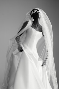 Mark Ingram’s silk Mikado A-line gown with satin bias trim tank neckline. Theia veil; Jennifer Behr headpiece and earring; Christian Dior sunglasses; Pronovias gloves; Wempe diamond earrings, diamond chain bracelets and diamond ring; De Beers diamond rings.
