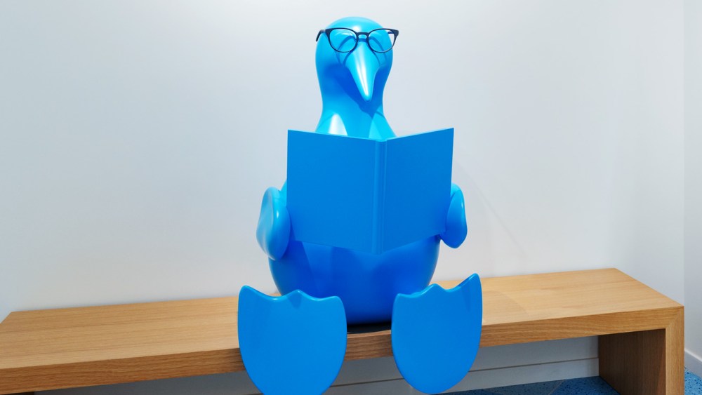 blue bird sculpture sitting with book  wearing warby parker glasses