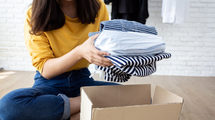 Woman holding Clothes with Donate Box In her room, Donation Concept.